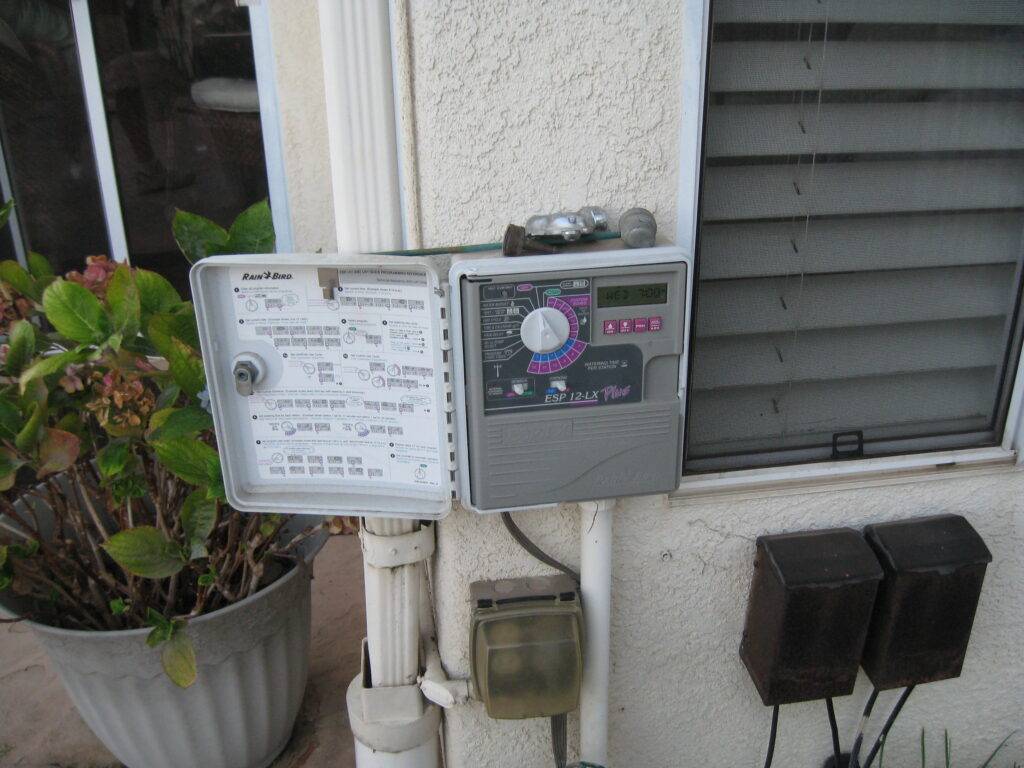 Sprinkler timer/controller box on the outside of a home, open with the controls visible