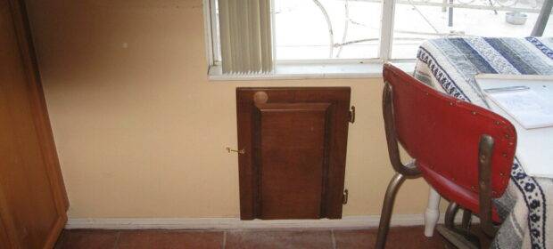 Wooden pet door installed under a window