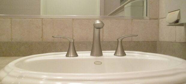 Modern faucet in bathroom, brushed nickel finish, simple & sleek curved geometry design