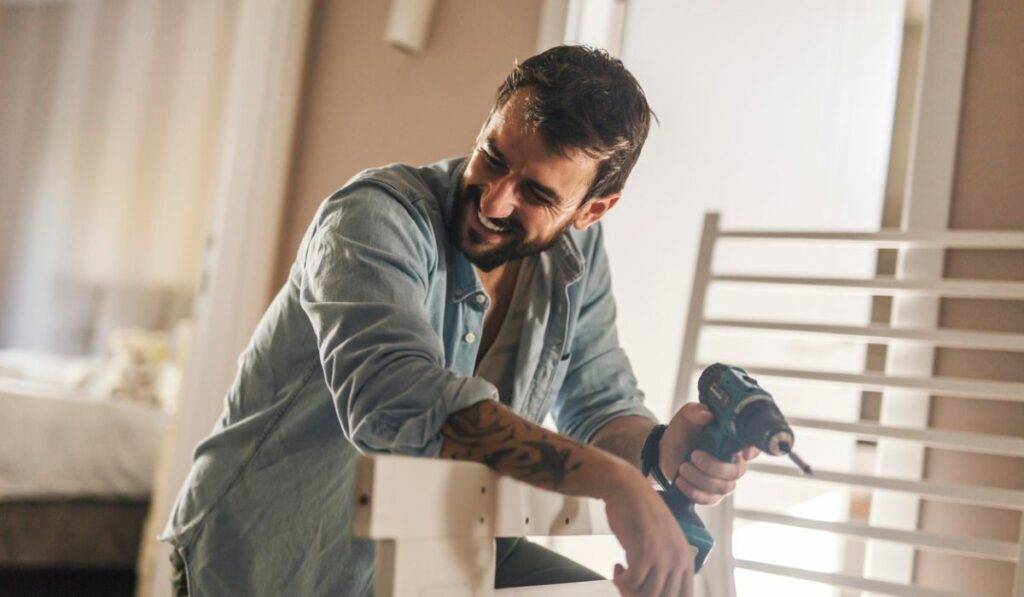 A man using a cordless drill at home.